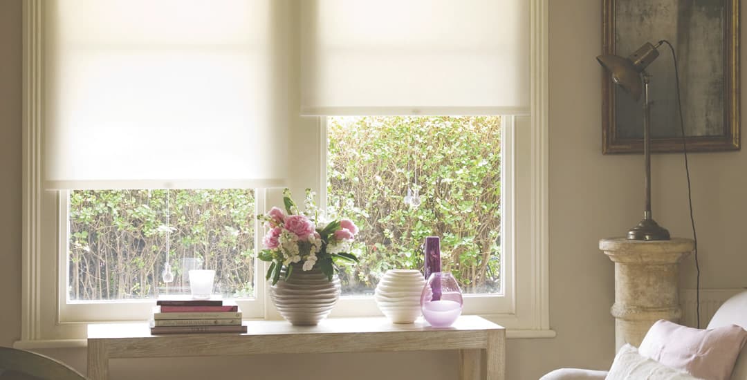 White dimout roller blinds in cosy sunny sitting room 