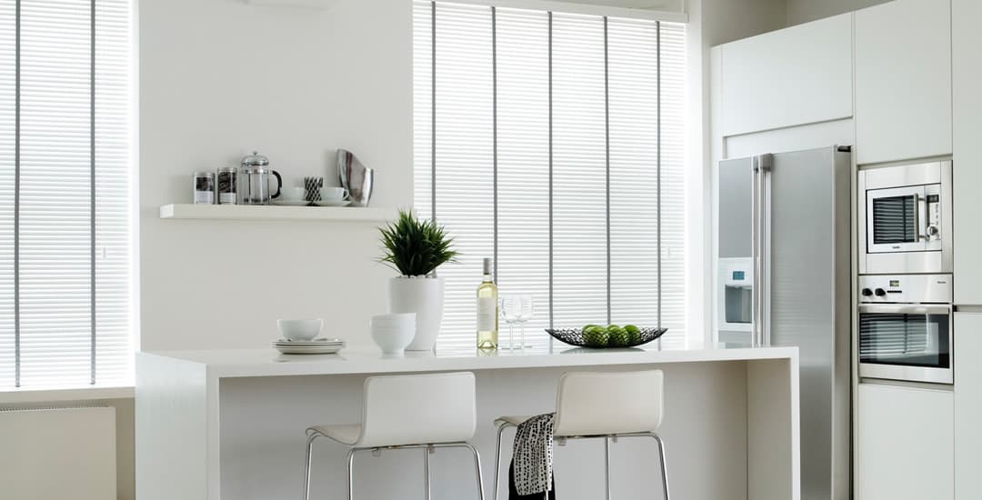 White wooden blinds with grey tapes in a modern white kitchen