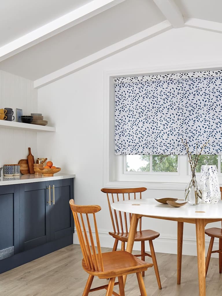 Blue silhouette leaf patterned roller blind in a gabled kitchen diner