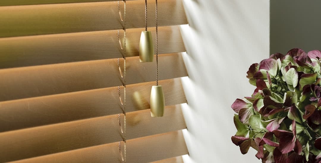 Closeup of closed honey wooden blinds in a sunny window