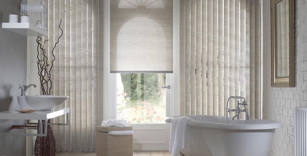 Mixture of silver-grey vertical and roller blinds on a large bathroom window