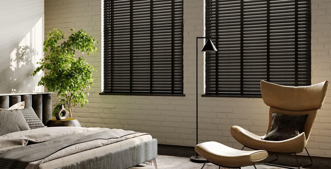 Partially closed black wooden venetian blinds in bedroom