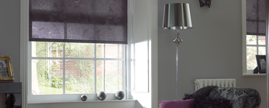 Purple patterned room darkening roller blinds in a sitting room