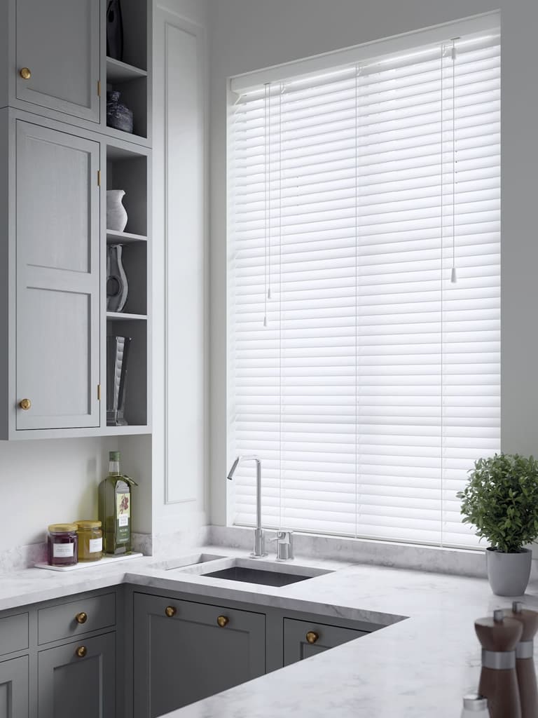 White faux wood blinds in a small modern grey kitchen