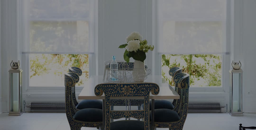 Sheer roller blinds in a dining room at dusk