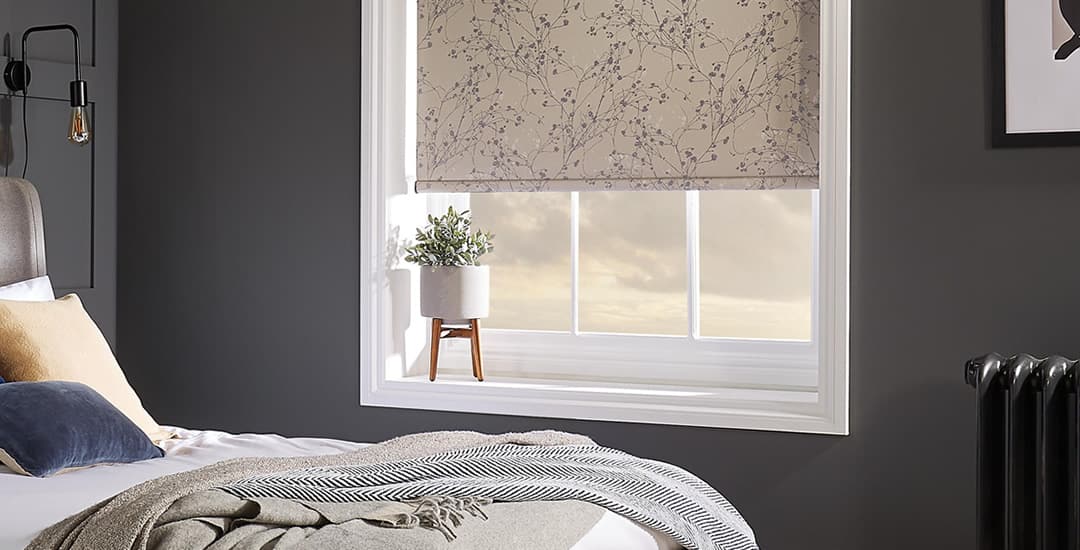 Beige floral patterned roller blind fitted inside recess in a dark grey bedroom