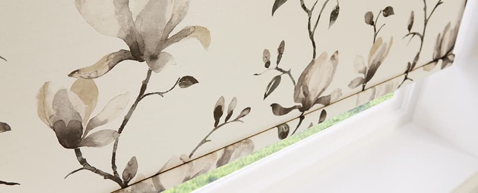 Closeup of beige floral patterned roller blind in a window