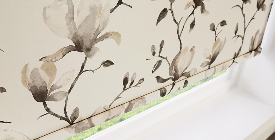 Closeup of beige floral patterned roller blind in a window