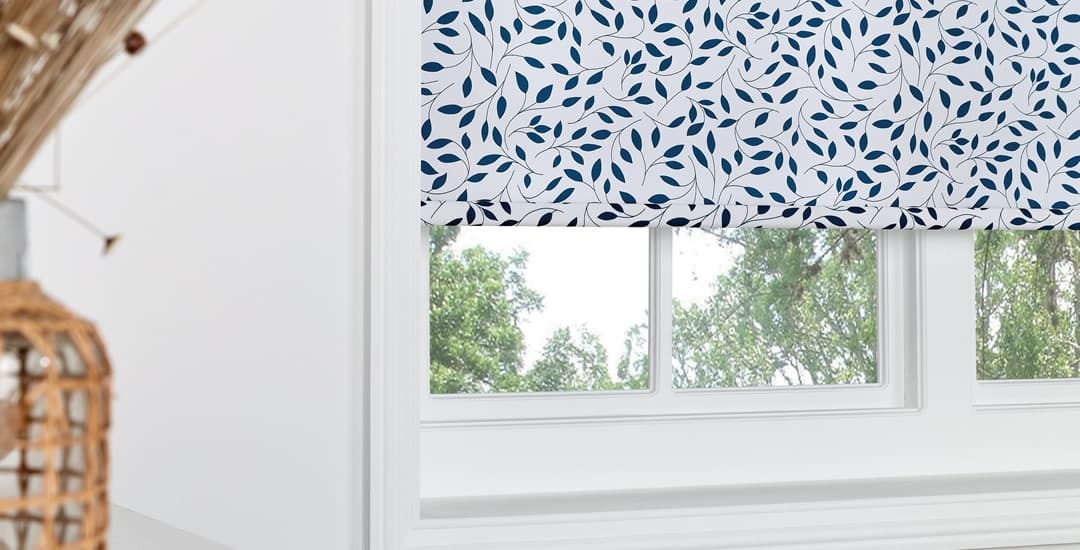 Closeup of navy blue and white leaf patterned roller blinds in a white wooden window frame