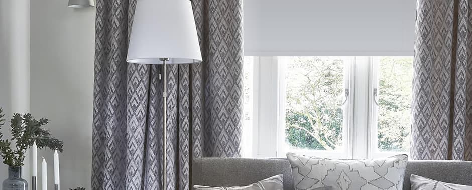 Grey blackout roller blind inside the window recess and curtains outside