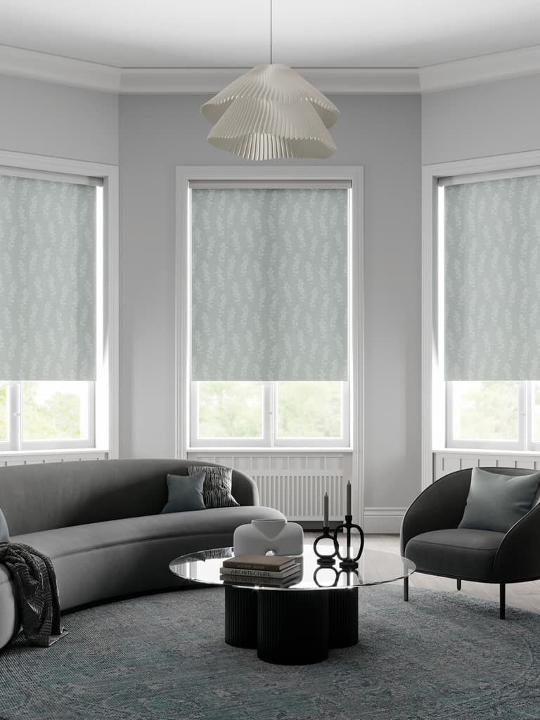 Grey-green textured floral roller blinds in a modern black and grey living room