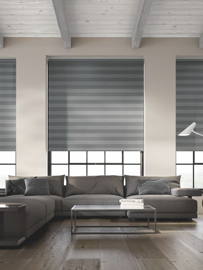 Grey striped roller blinds in a large modern living room with high ceiling and beams
