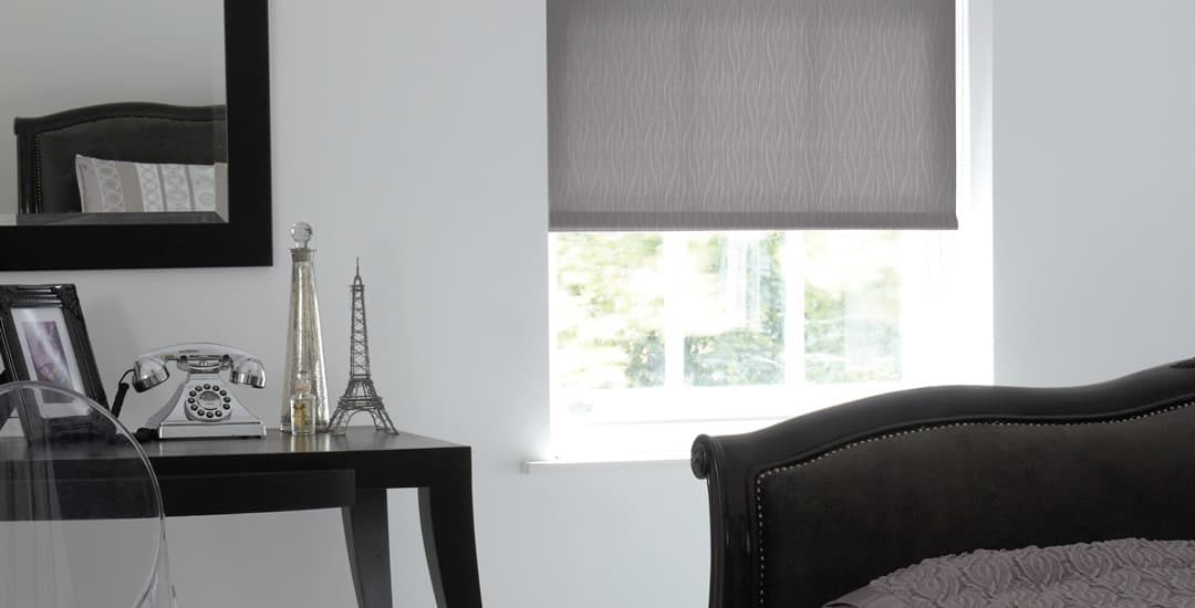 Made-to-measure grey roller blinds in a small bedroom window