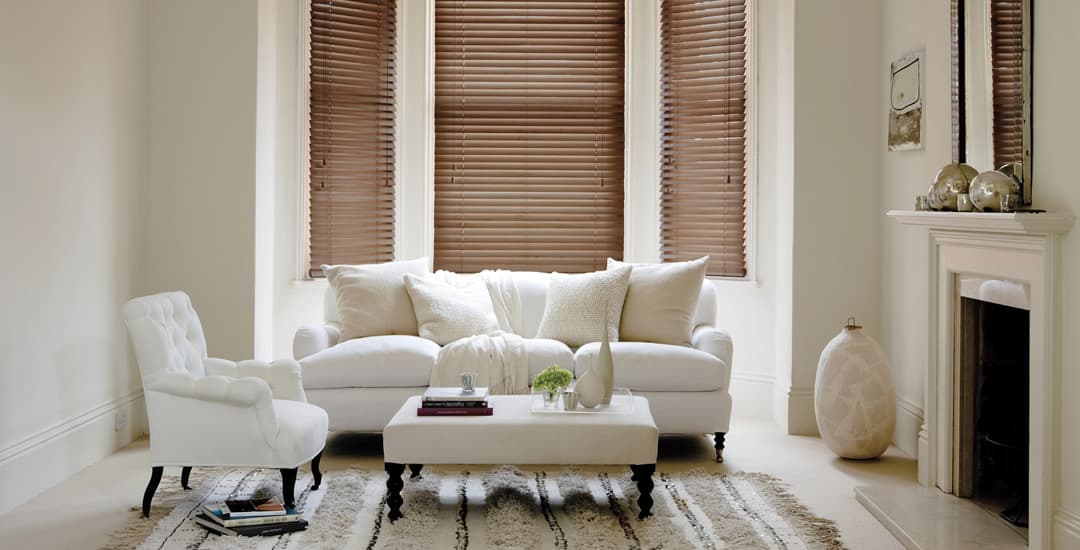 Made-to-measure walnut wooden blinds in a cosy cream living room