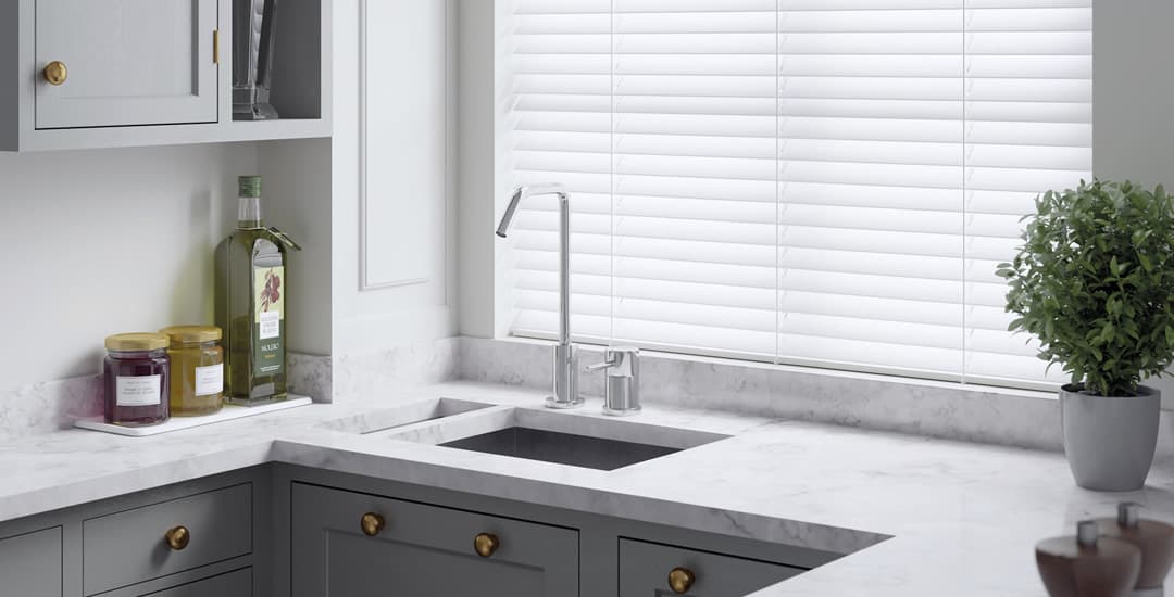 White faux wooden Venetian blinds in a modern grey kitchen