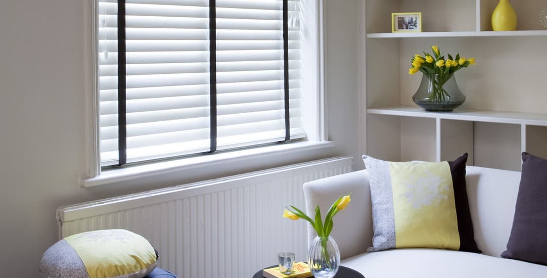 White wooden blinds with black tapes in a small contemporary living room