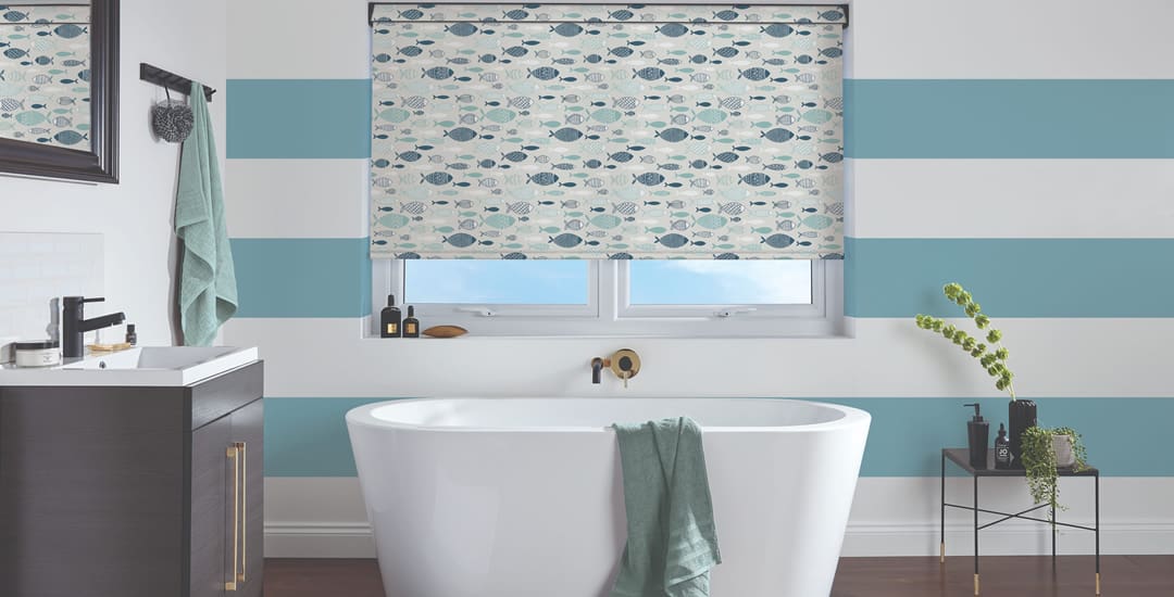 Fish patterned roller blinds in a blue and white striped bathroom