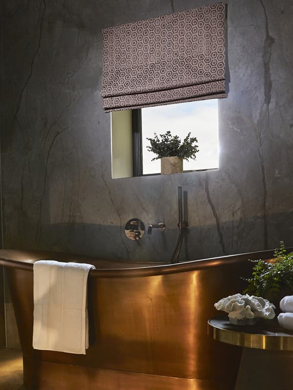Roman blind in a bathroom with copper bath