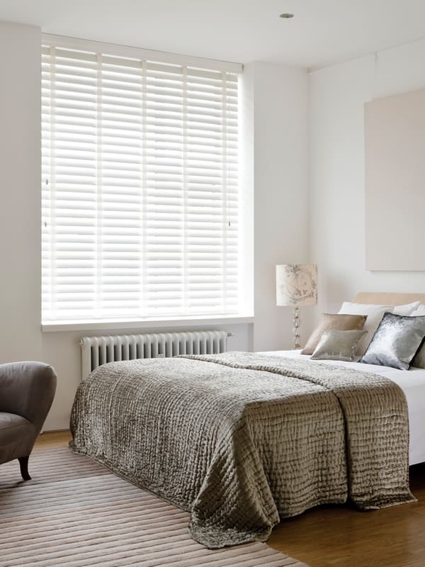 Stylish white wooden horizontal blinds with tapes in a luxury bedroom