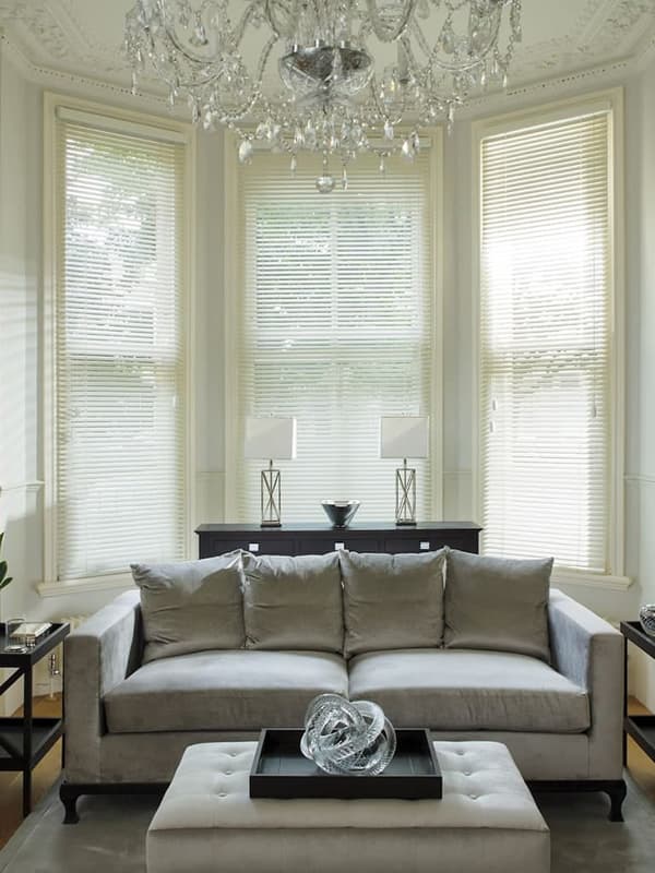 Cream wooden venetian blinds in a plush high ceilinged living room