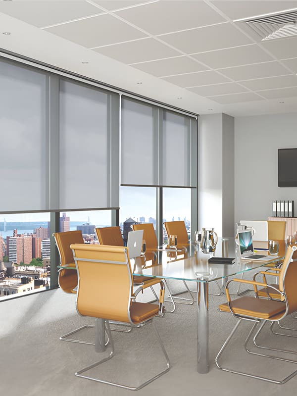 Grey light filtering commercial roller blinds in meeting room
